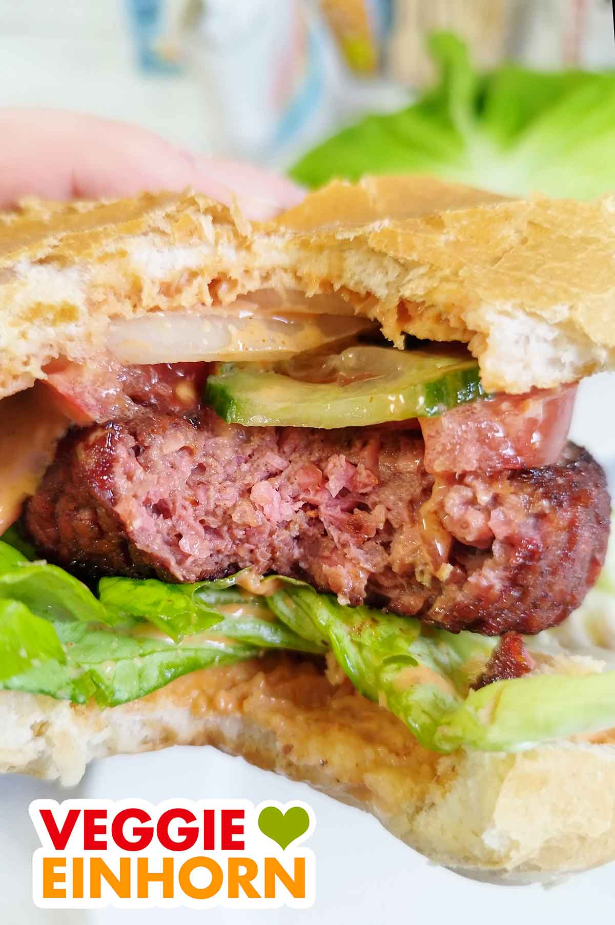 Eine Hand hält den angebissenen burger mit einem Patty von Food for Future by Penny