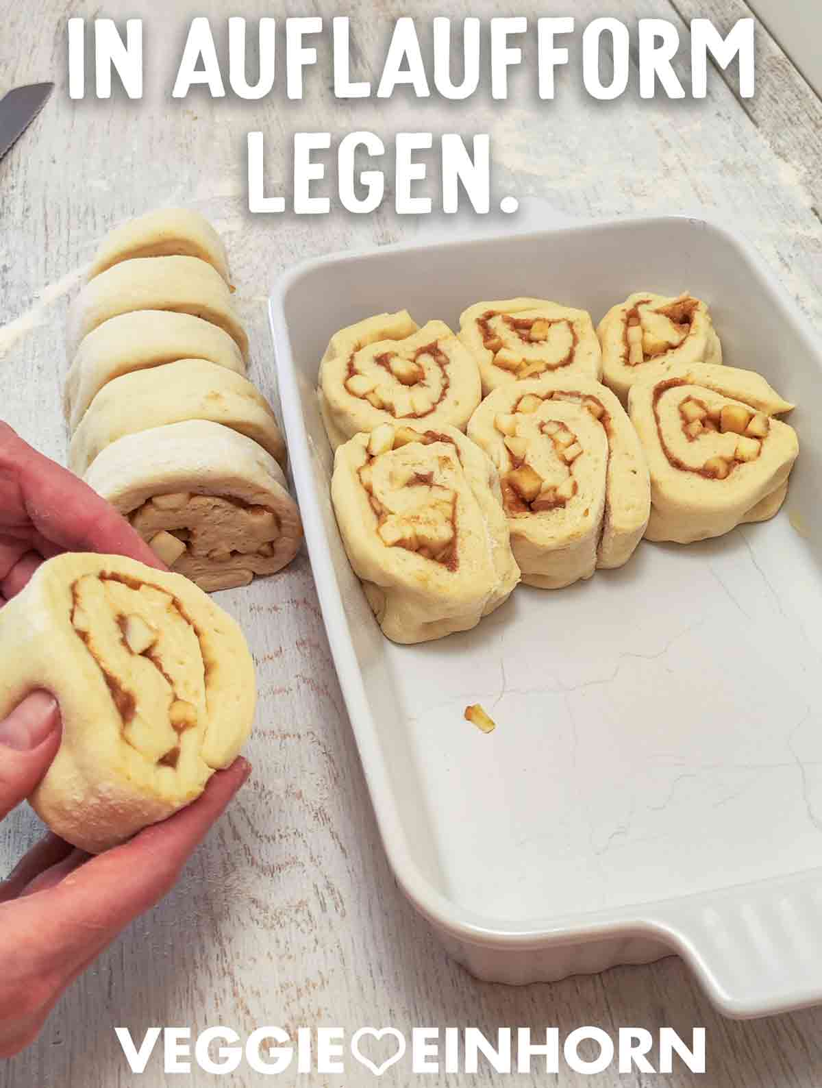 Aufgeschnittene Apfel-Zimt-Schnecken werden in eine weiße Auflaufform gelegt.
