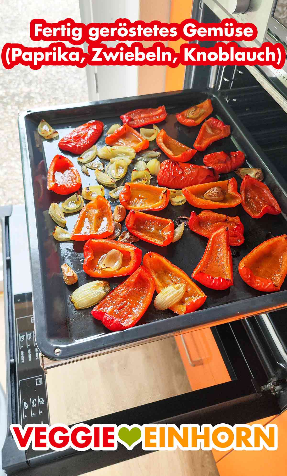 Backblech mit im Ofen gerösteten roten Paprika, Zwiebeln und Knoblauchzehen