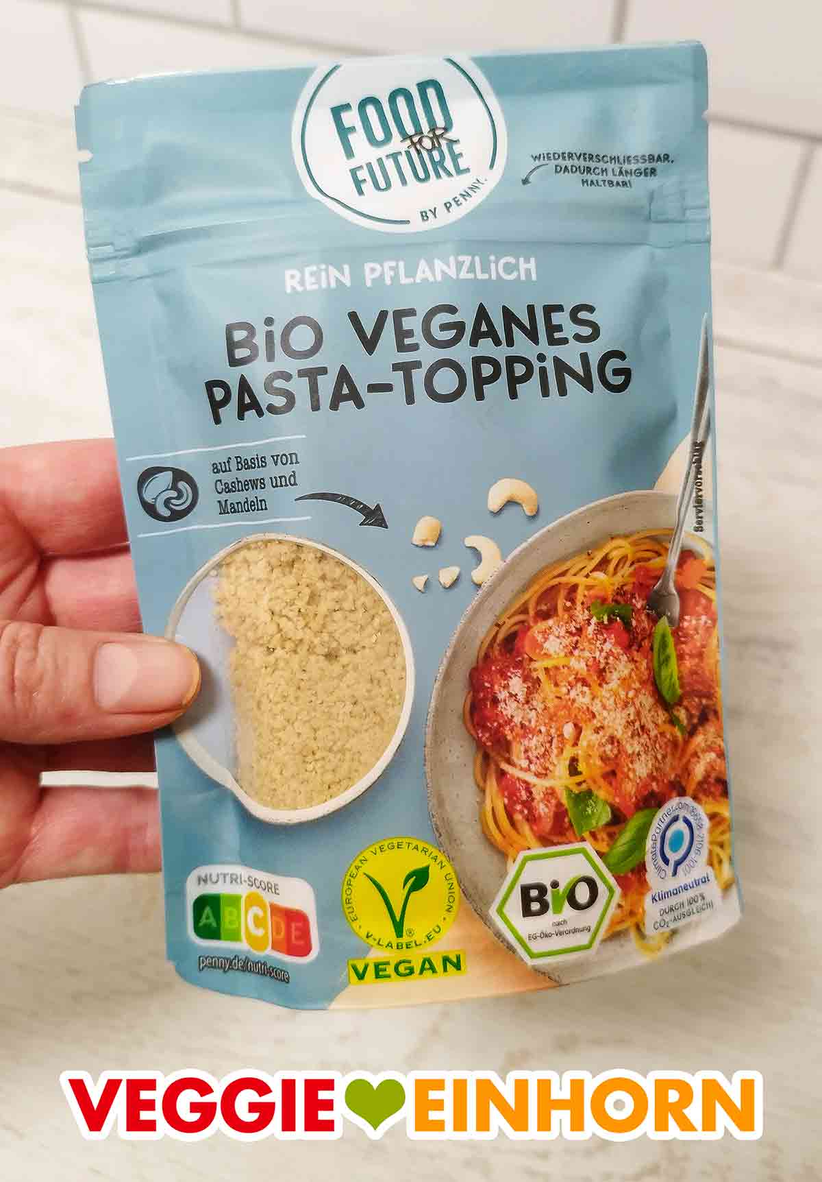 Eine Hand hält einen Beutel mit Bio Veganem Pasta Topping von Penny
