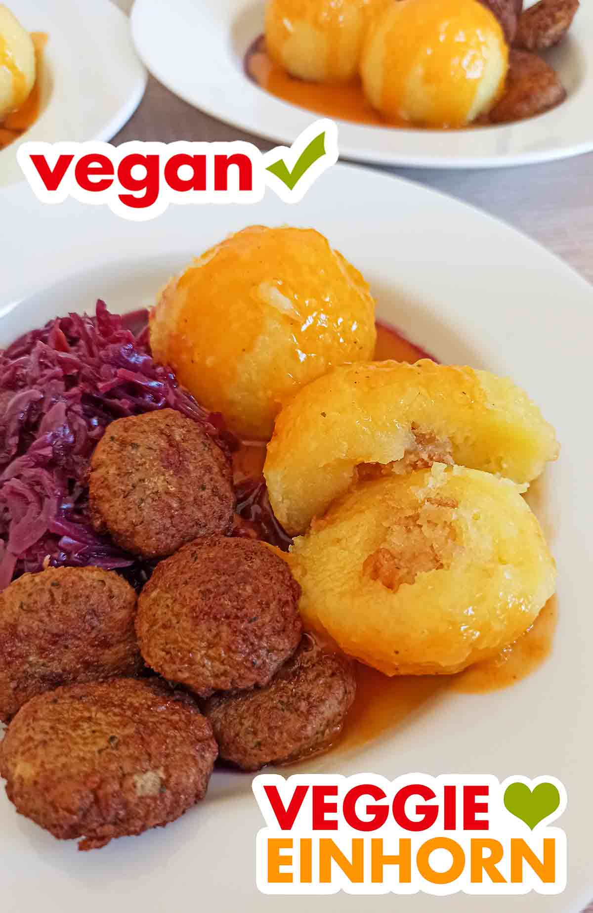 Hier sieht man die leckere Brotwürfel Füllung der veganen Sonntagsknödel. Ein zerteilter Sonntagsknödel mit Croutons Füllung auf einem Teller mit Rotkohl, veganer Bratensoße und veganen Frikadellen.