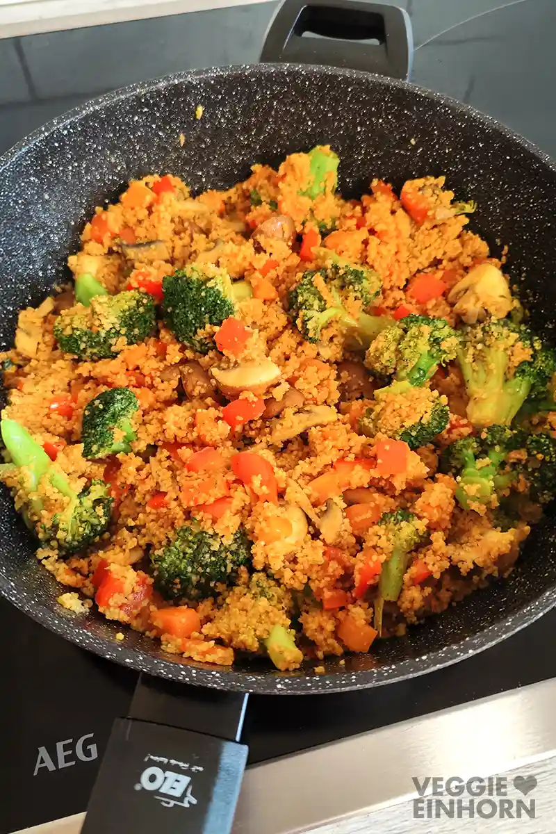 Eine schwarze Pfanne mit Couscous und Gemüse.