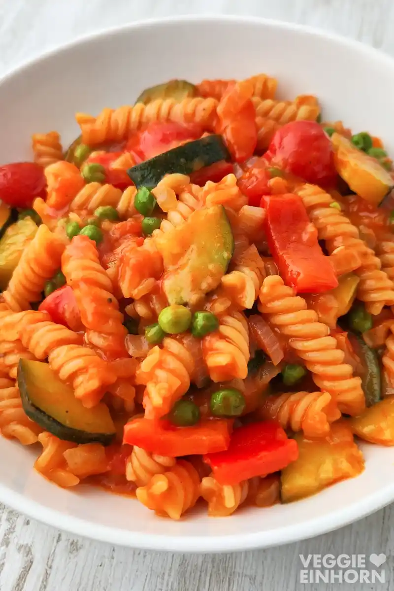 Cremige vegane One Pot Pasta mit Fusilli, Zucchini, Paprika, Erbsen und Tomaten in würziger Currypaste-Kokosmilch-Sauce.