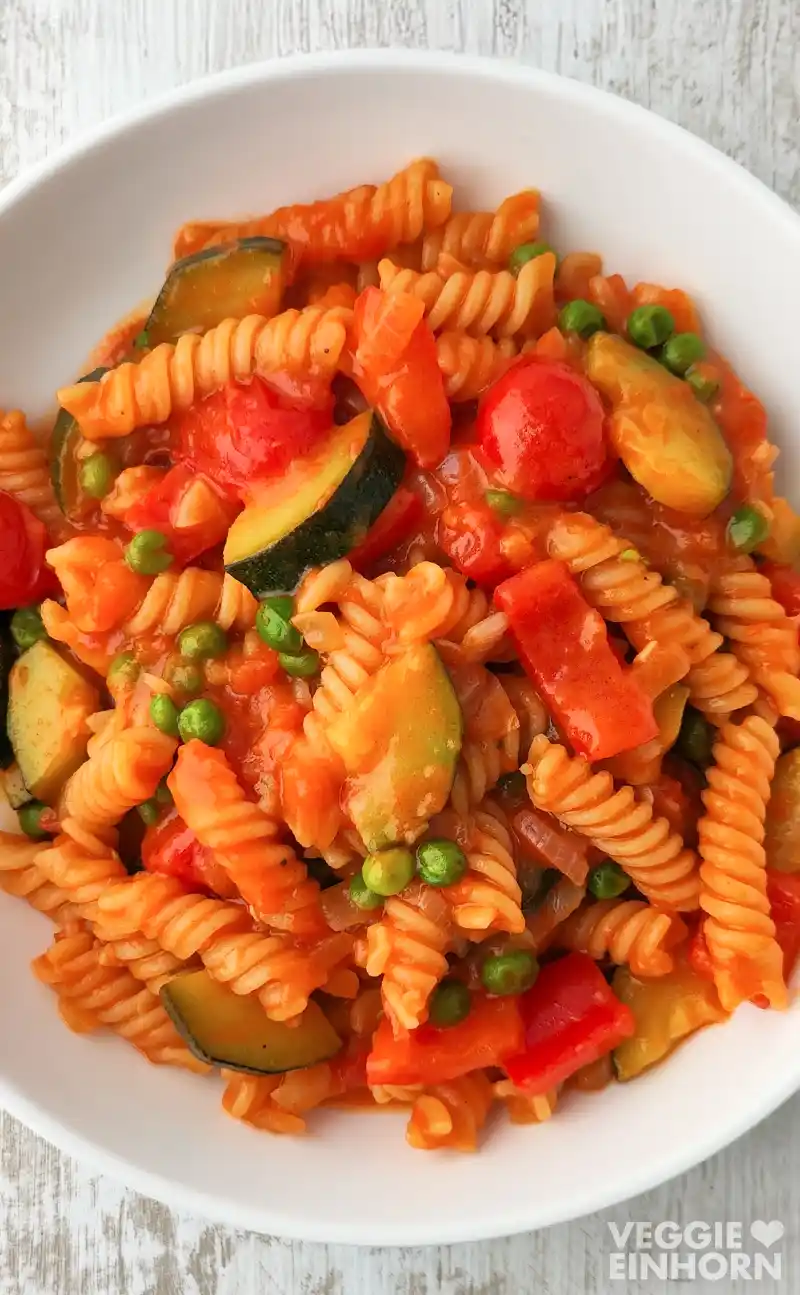 Teller mit veganer One Pot Pasta mit Gemüse und einer cremigen Soße aus Kokosmilch und Currypaste.