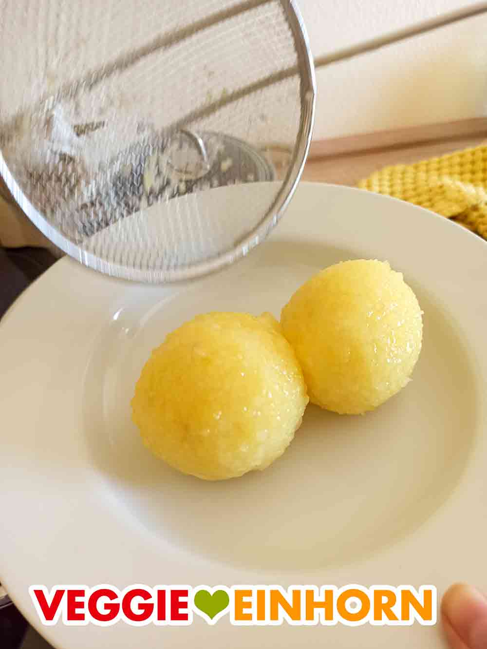 Die fertig gegarten veganen Sonntagsknödel sehen sehr appetitlich aus. Zwei Burgis Sonntagsknödel werden auf einen Teller gegeben.