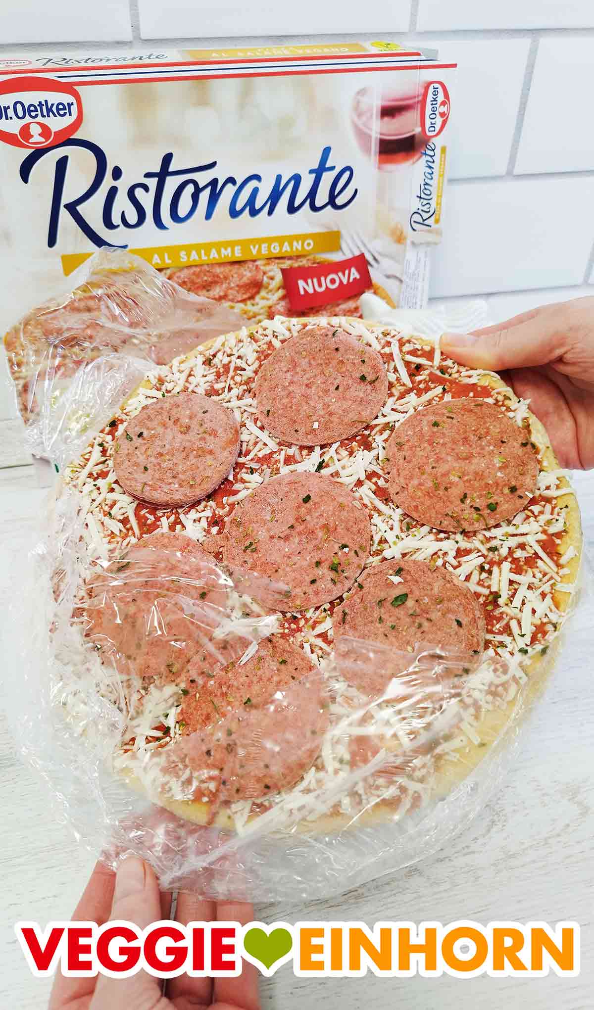 Entfernen der Folie von der tiefgekühlten veganen Salami Pizza