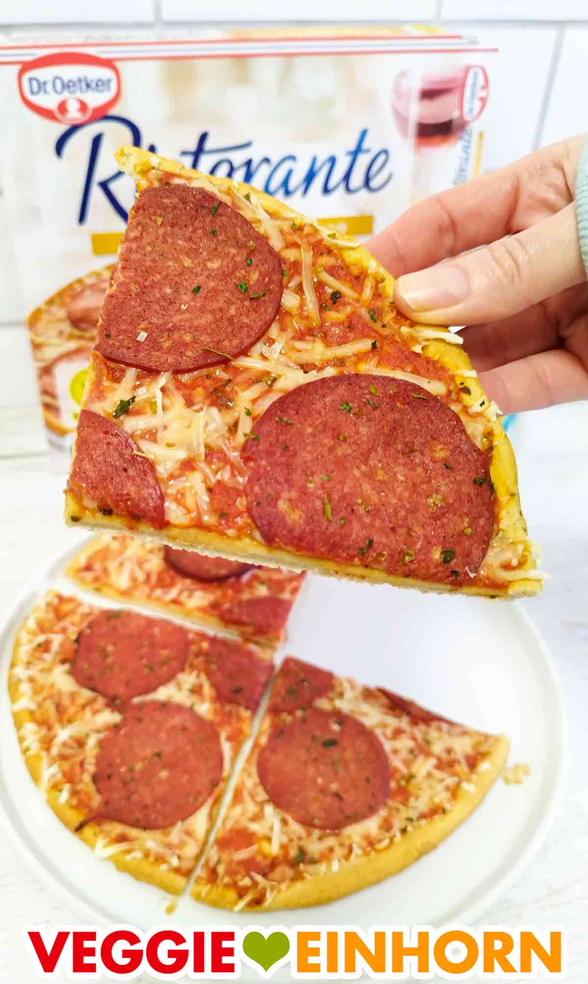 Eine Hand hält ein Stück vegane Salami Pizza Ristorante