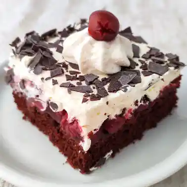Ein einzelnes Stück vegane Schwarzwälder Kirschtorte vom Blech mit lockerer Schokoschicht, Kirschfüllung, Sahnehaube und Schokoraspeln.