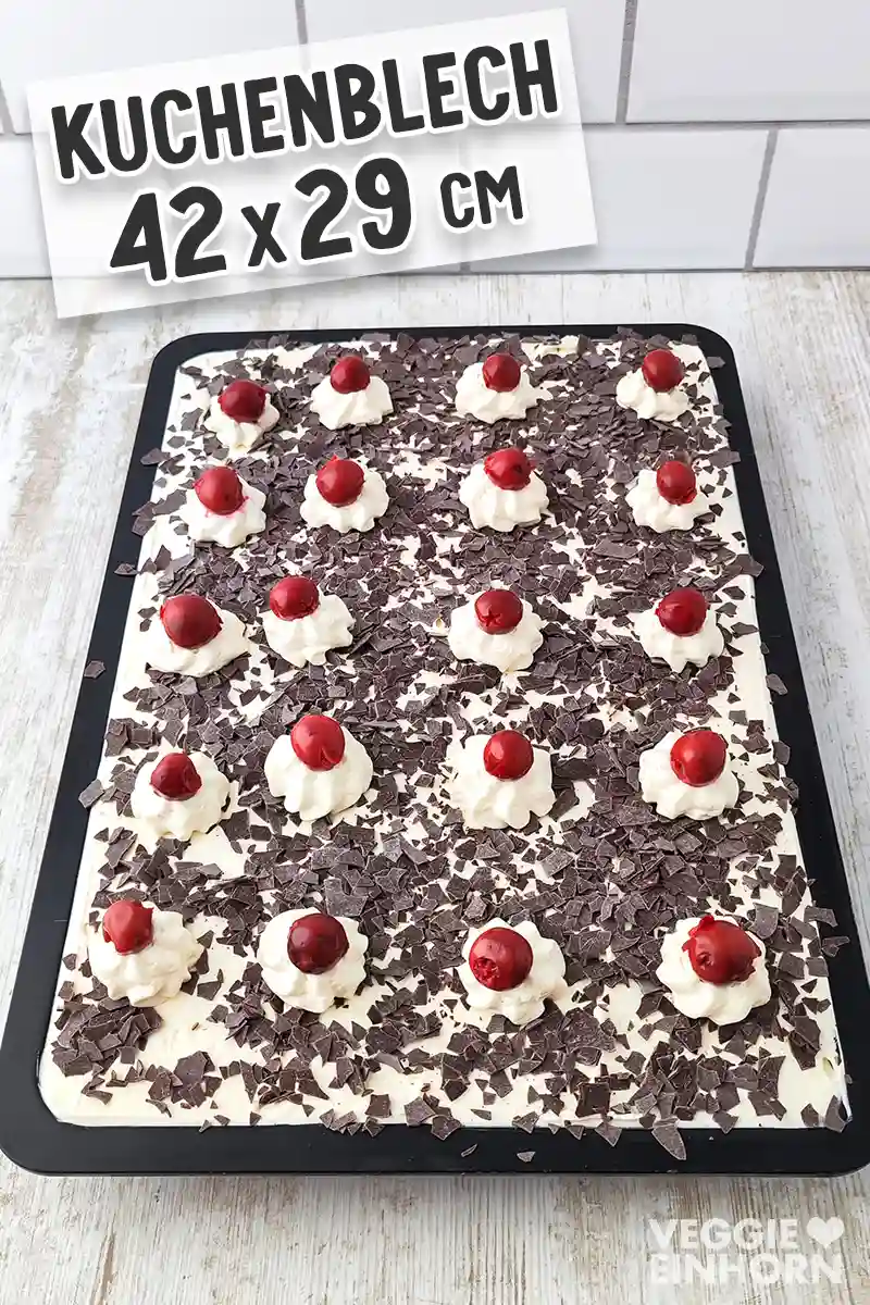 Ein ganzes Blech vegane Schwarzwälder Kirschtorte mit Sahnetupfen, Kirschen und Raspelschokolade, darüber steht der Text Kuchenblech 42 x 29 cm.