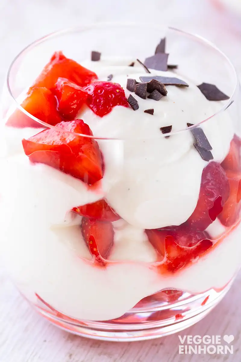 Veganes Erdbeer-Dessert im Glas mit frischen Erdbeeren, veganer Dessertcreme und dunklen Schokoraspeln als Topping.