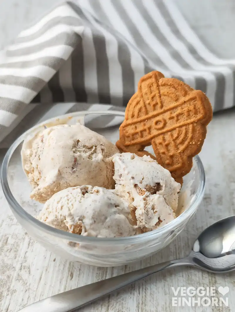 Veganes Spekulatius Eis Veganes Spekulatius Eis einem Spekulatius Keks in einer Glasschale, im Hintergrund ein gestreiftes Tuch.