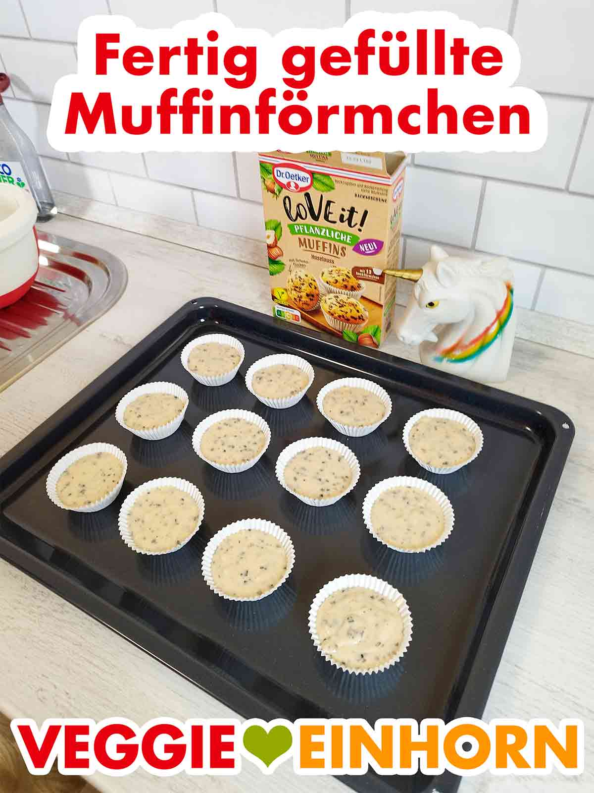 12 mit Muffinteig gefüllte Förmchen auf dem Backblech