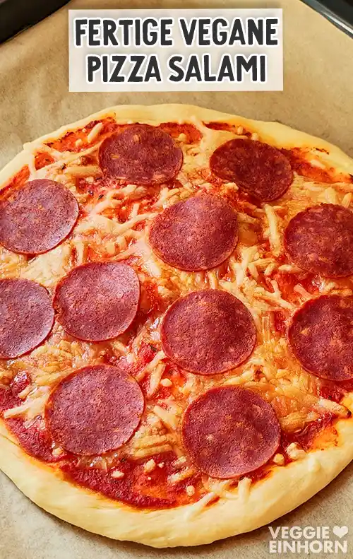 Frisch gebackene runde Pizza mit goldbraunem Rand, geschmolzenem veganem Käse und runden Scheiben veganer Salami, darüber Textaufschrift Fertige vegane Pizza Salami.