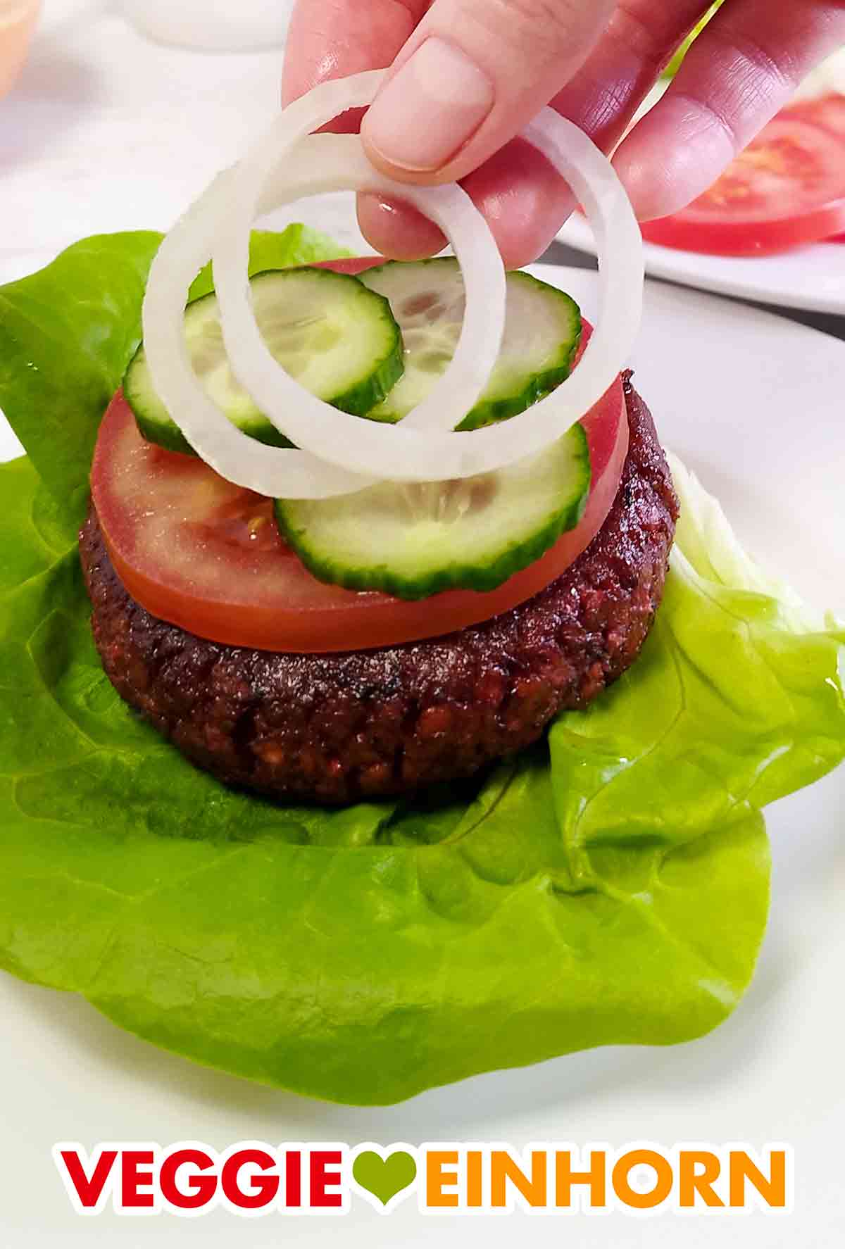 Gurkenscheiben und Zwiebelringe auf dem veganen Burger