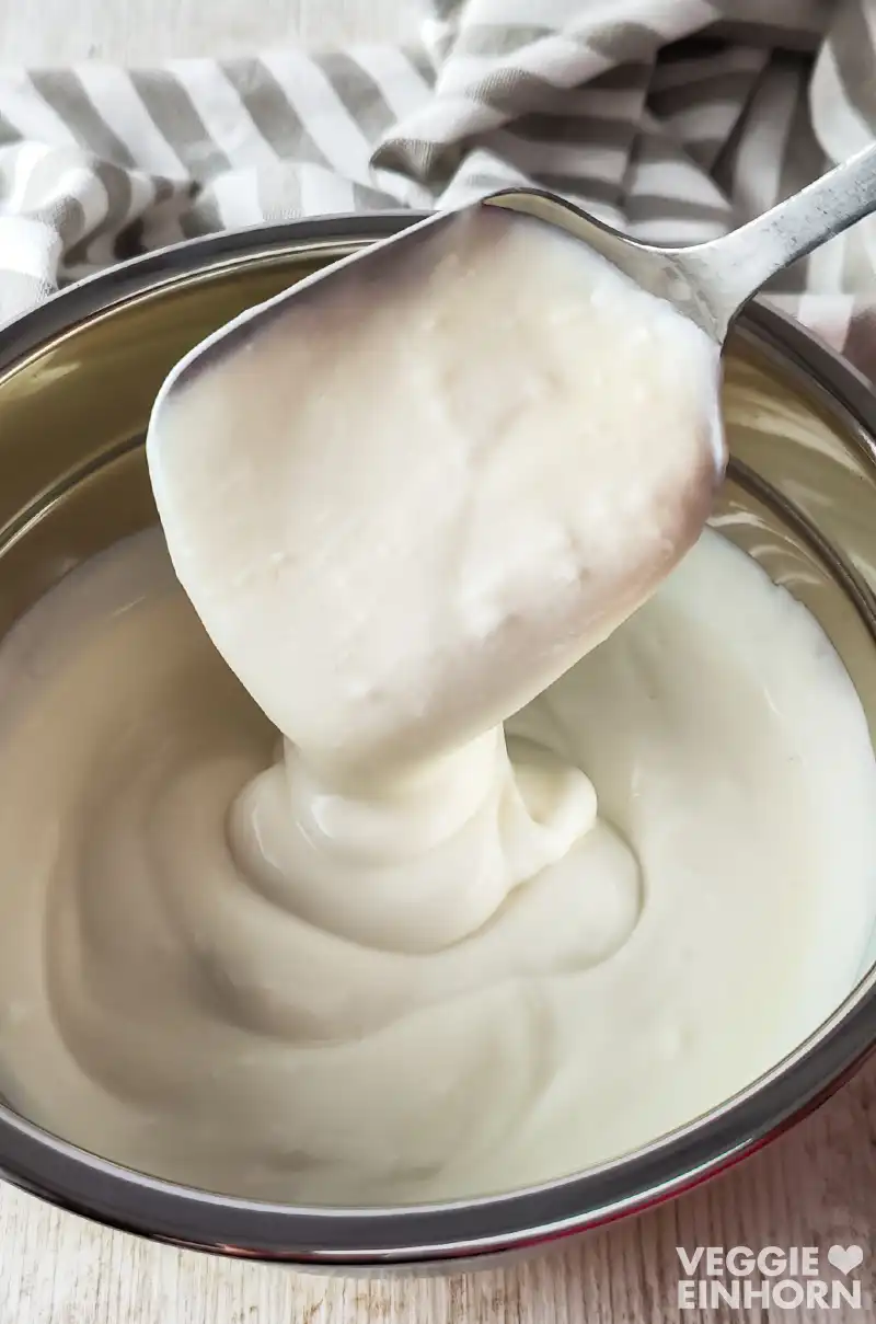 Cremige vegane Joghurtsoße in einer Schüssel und auf einem Löffel.