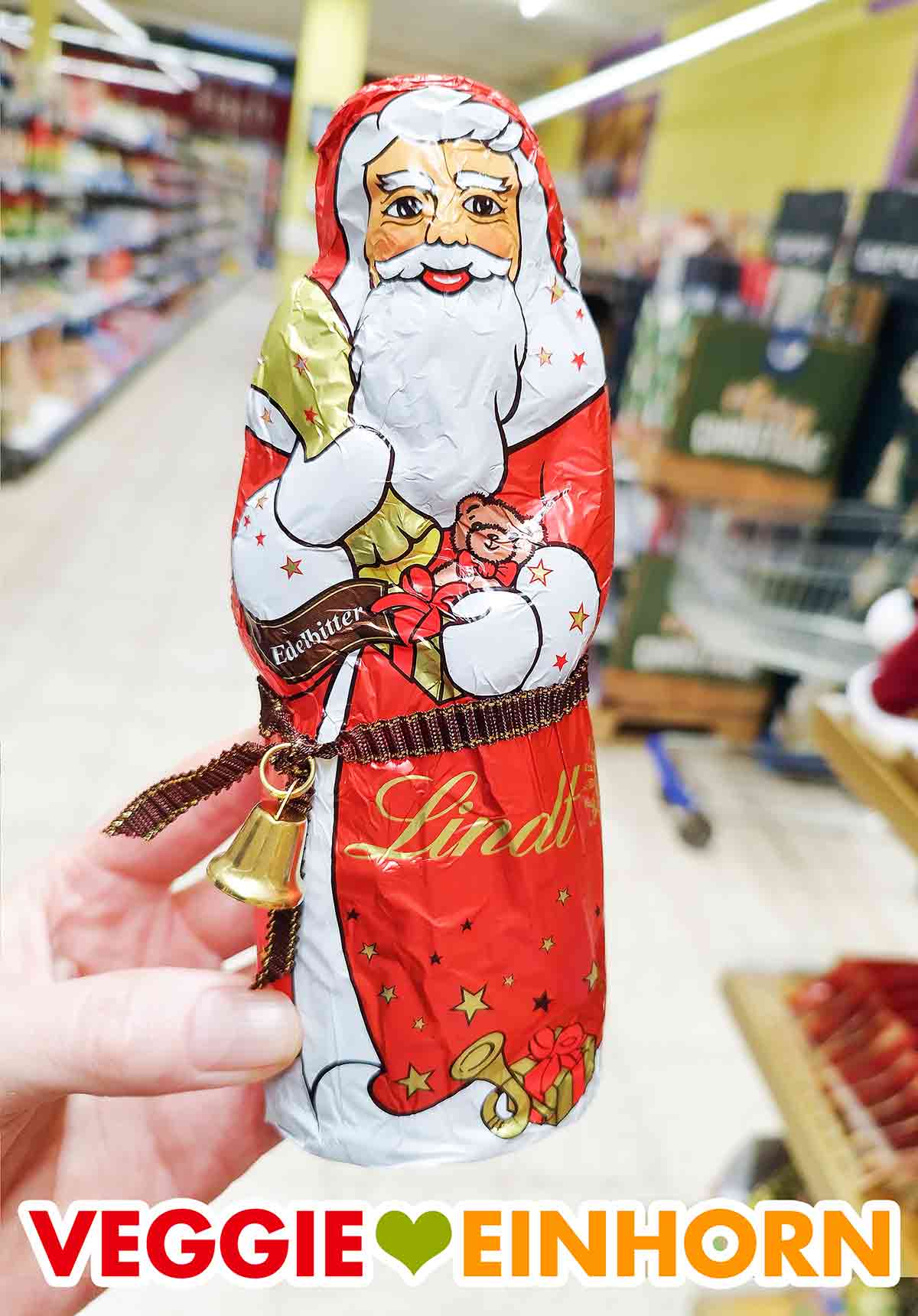 Eine Hand hält einen Lindt Edelbitter Weihnachtsmann im Supermarkt