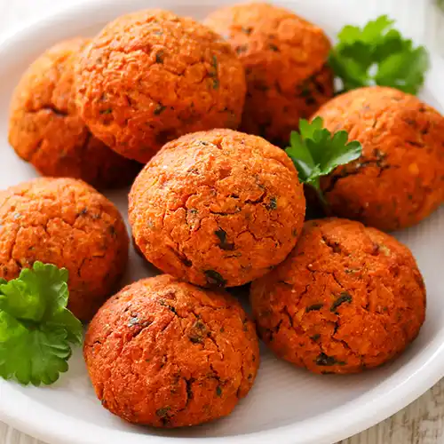 Vegane Linsenbällchen auf einem weißen Teller, garniert mit frischer Petersilie.