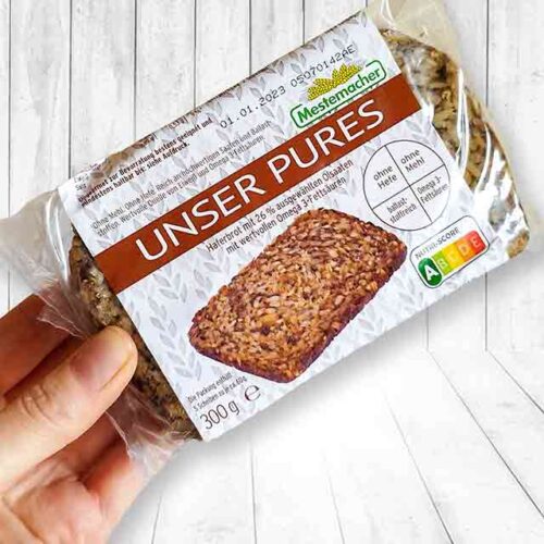 Eine Hand hält eine Packung Mestemacher Unser Pures