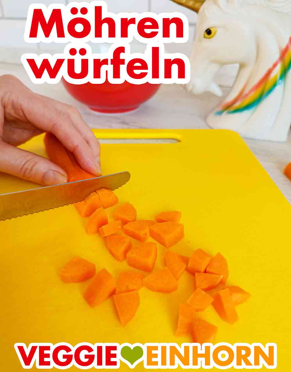 Eine Karotte wird auf einem Schneidebrett mit einem Messer in kleine Stücke geschnitten