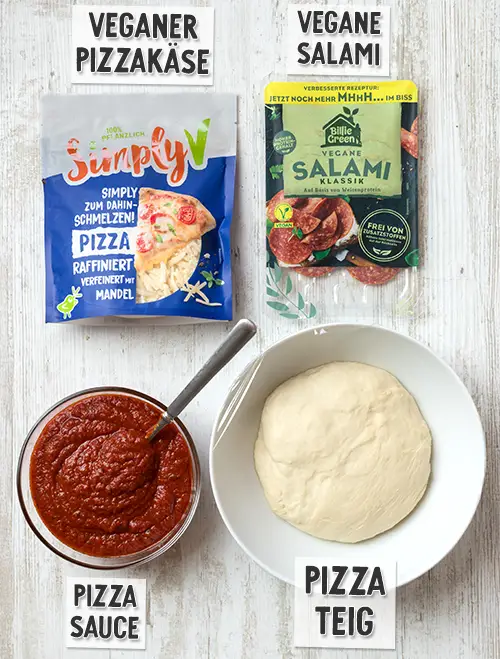 Zutaten für eine vegane Salami Pizza: Eine Packung Simply V veganer Pizzakäse, eine Packung Billie Green vegane Salami Klassik, eine Schüssel mit roter Pizzasauce und eine Schüssel mit Hefeteig.