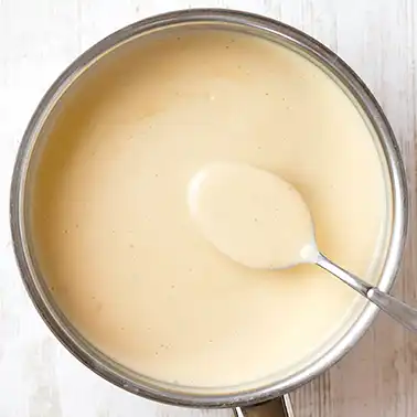 Vegane Béchamelsauce in einem Topf mit Löffel als Symbolbild für die Kategorie Rezepte für vegane Soßen.