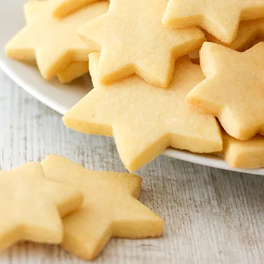 Nahansicht von veganen Butterplätzchen in Sternform auf einem weißen Teller als Kategoriebild für vegane Weihnachtsplätzchen.