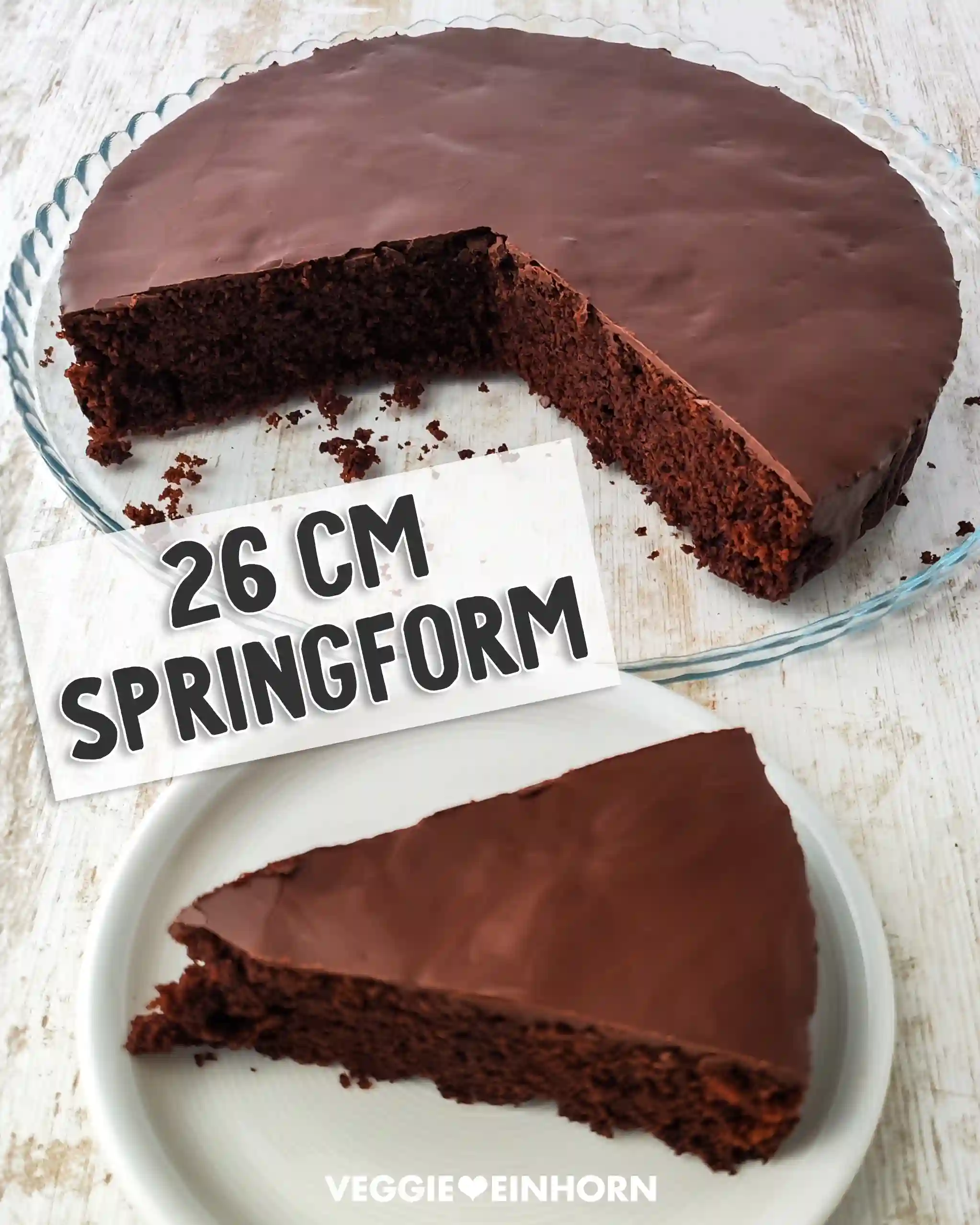 Runder veganer Schokokuchen mit Schokoglasur auf einer Glasplatte, ein Stück liegt auf einem weißen Teller im Vordergrund.