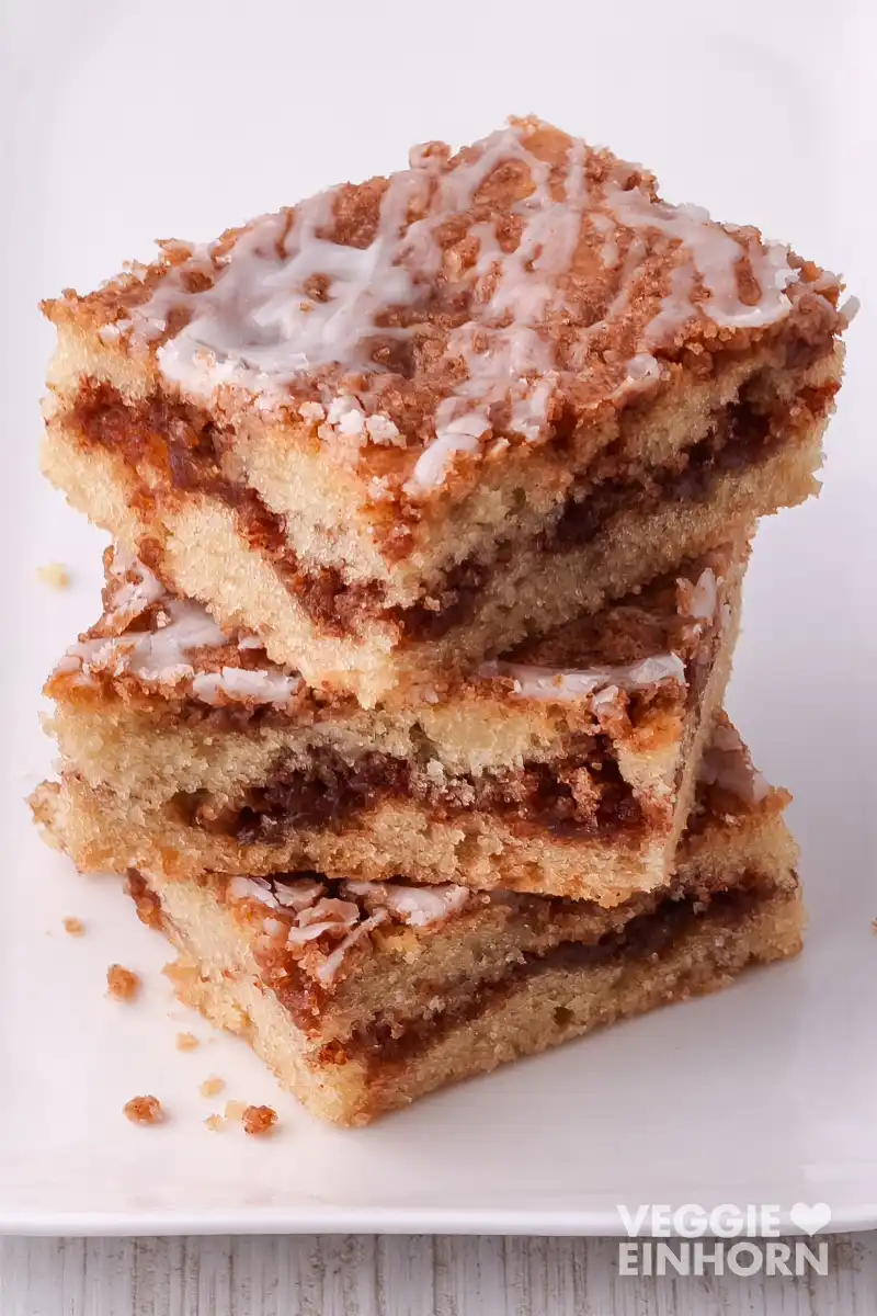 Drei übereinandergestapelte Zimtkuchenstücke mit sichtbarer Füllung und Zuckerguss.