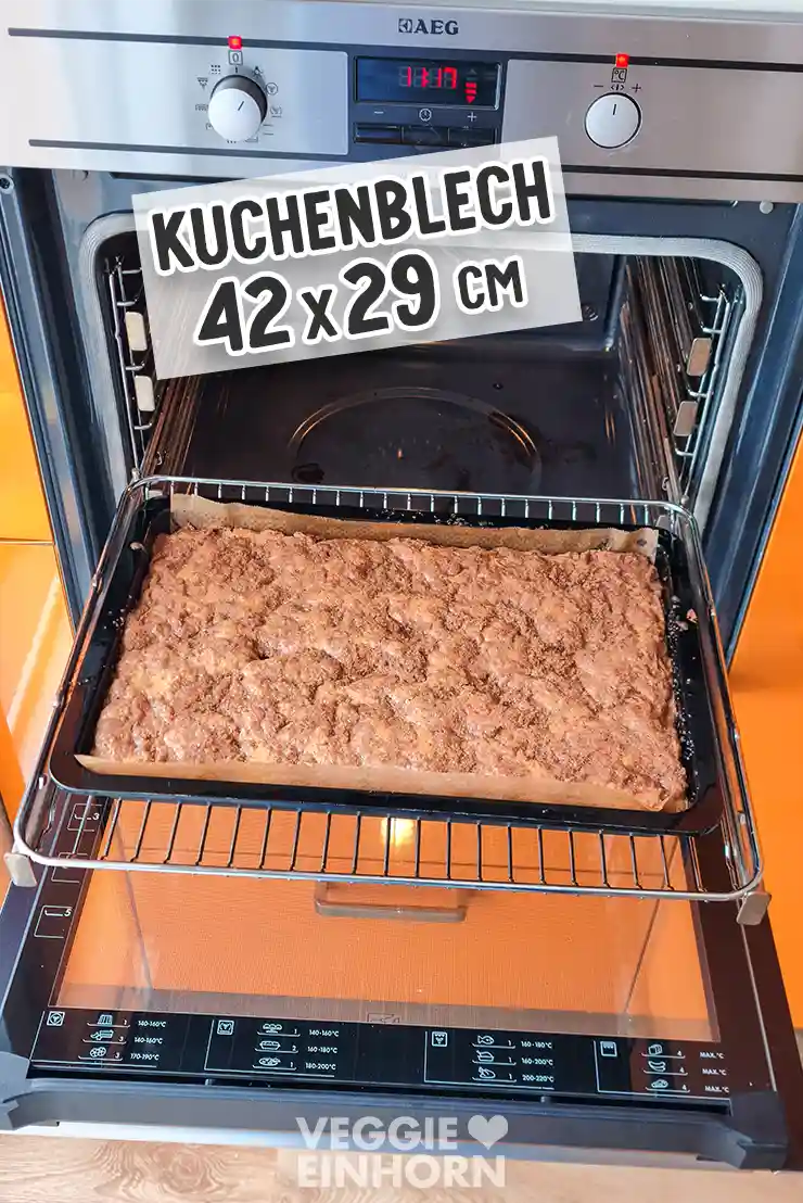 Backblech mit veganem Zimtkuchen vor dem geöffneten Backofen.
