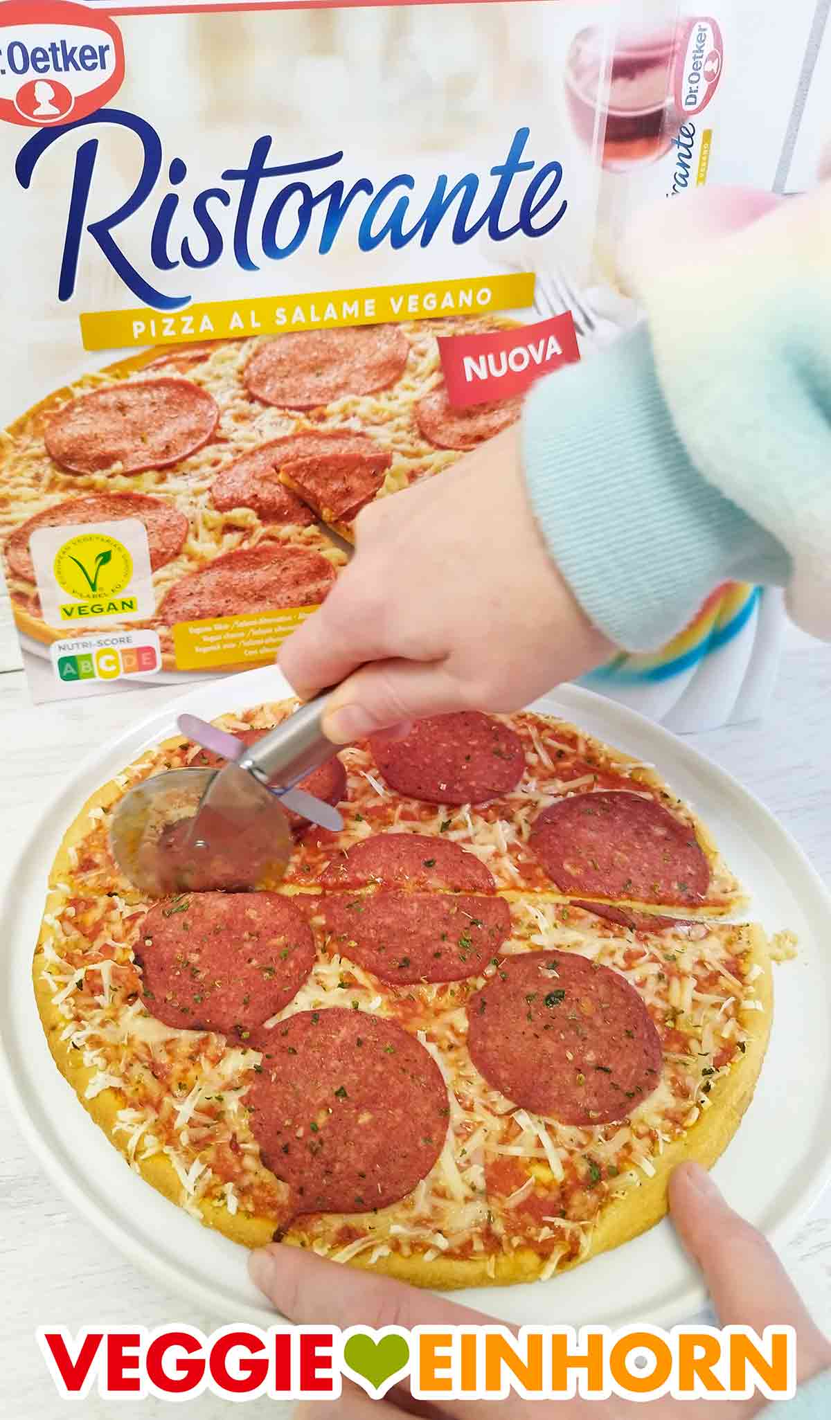 Schneiden der veganen Salami Pizza Ristorante mit einem Pizzaroller