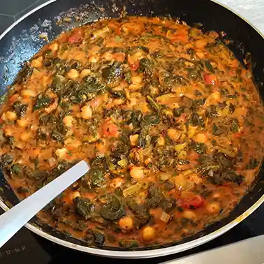 Pfanne mit einem Curry aus Spinat mit Kichererbsen, Tomaten und Kokosmilch.