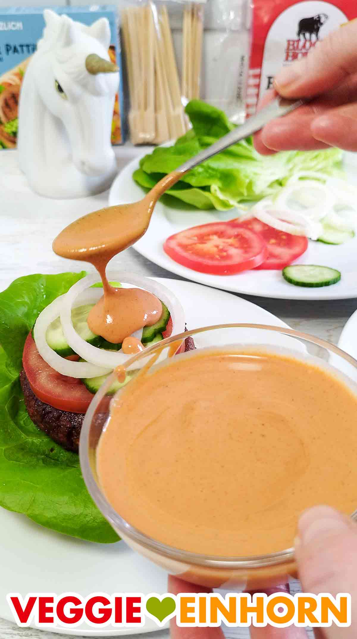 Selbstgemachte vegane Burgersauce wird auf den Burger gegeben.