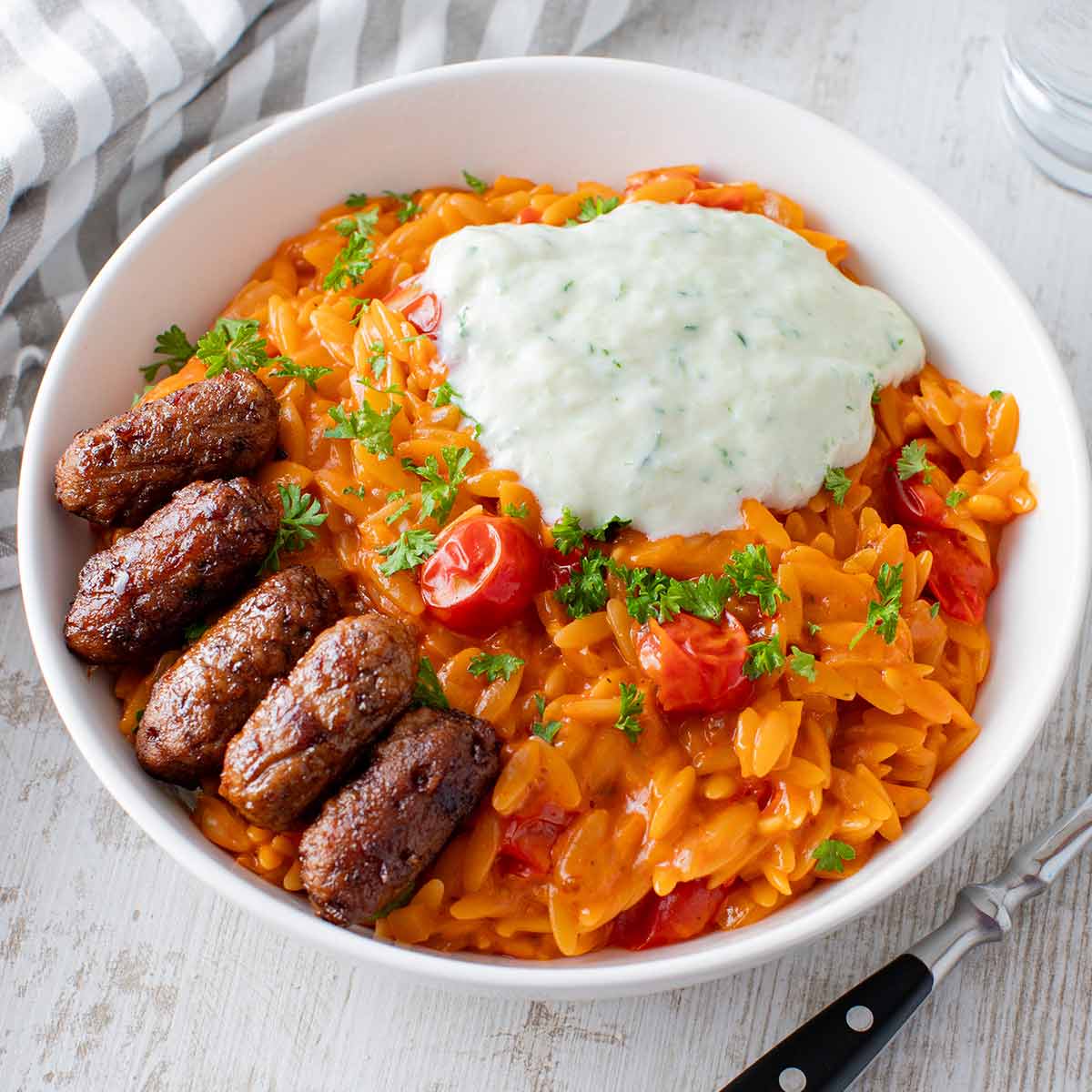 Tomaten Kritharaki mit veganem Tzatziki und veganen Cevapcici