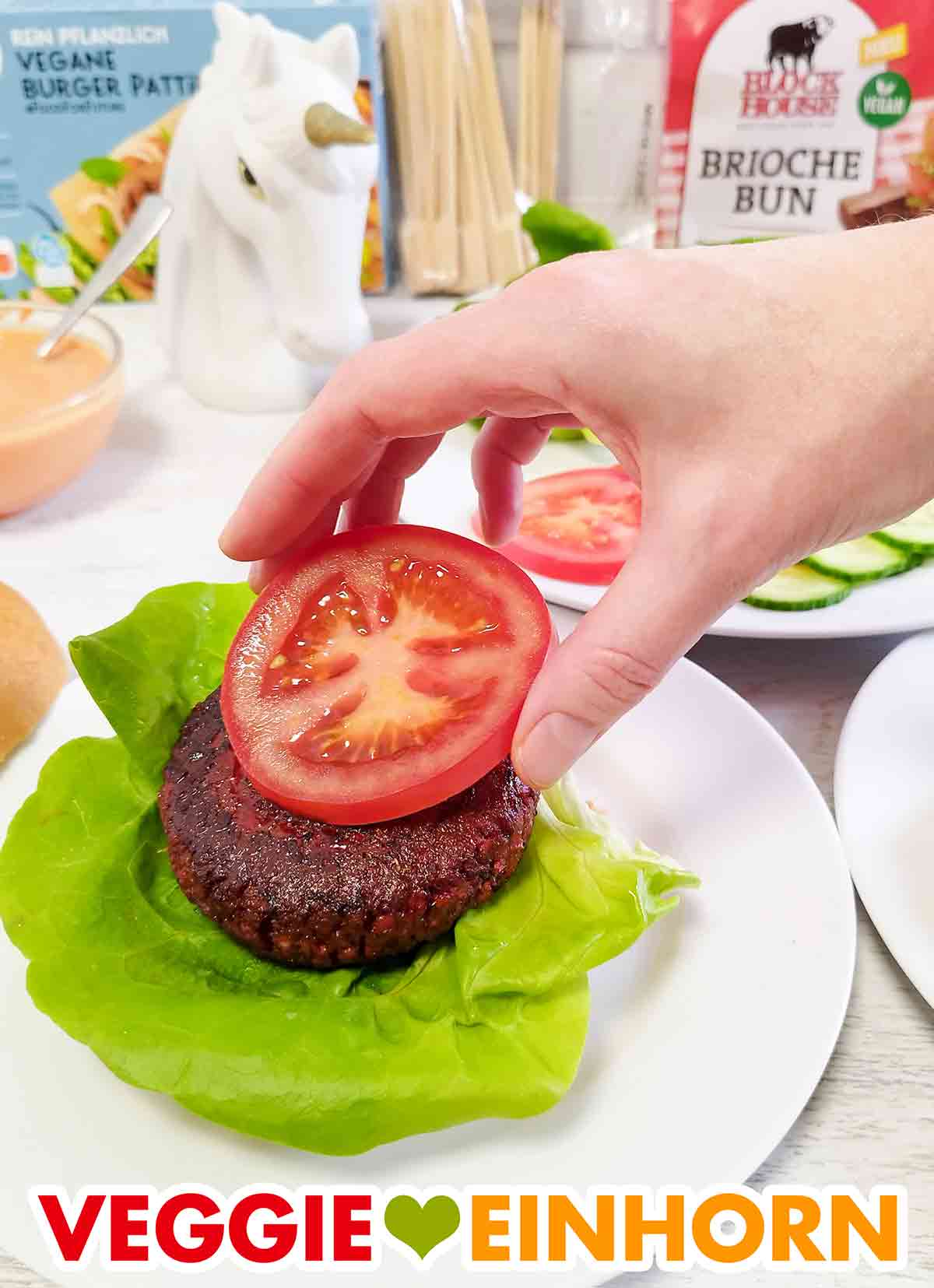 Auf den veganen Burger Patty von Penny wird eine Tomatenscheibe gelegt