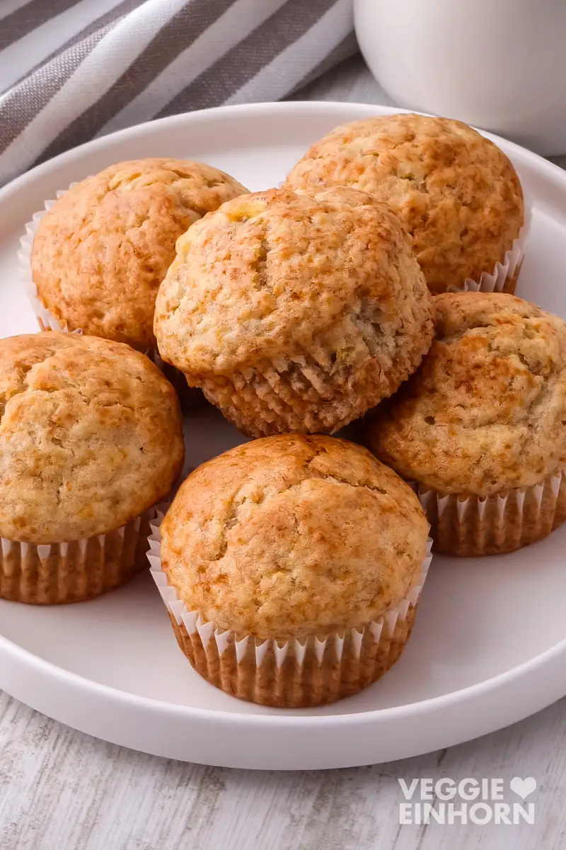 Vegane Bananenbrot Muffins Vegane Bananenbrot Muffins auf einem weißen Teller neben einem gestreiften Küchentuch.