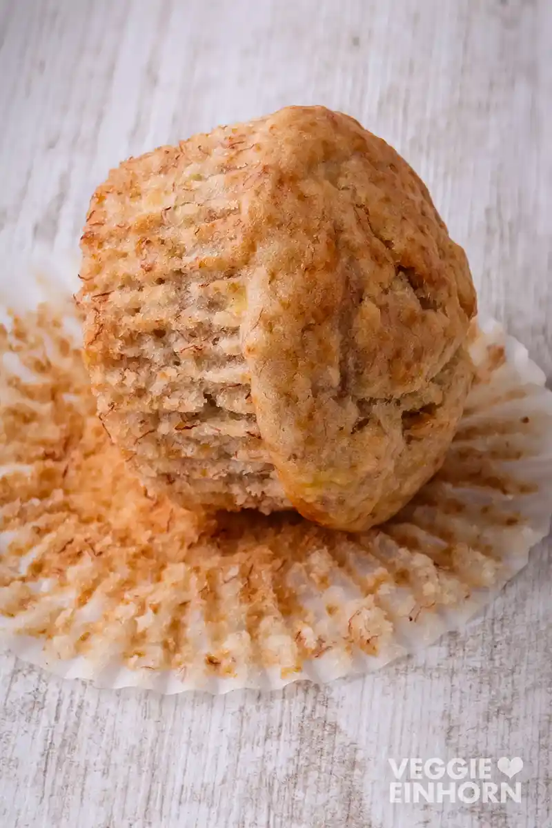 Saftiger veganer Bananenbrot Muffin auf dem aufgefalteten Papier-Muffinförmchen.