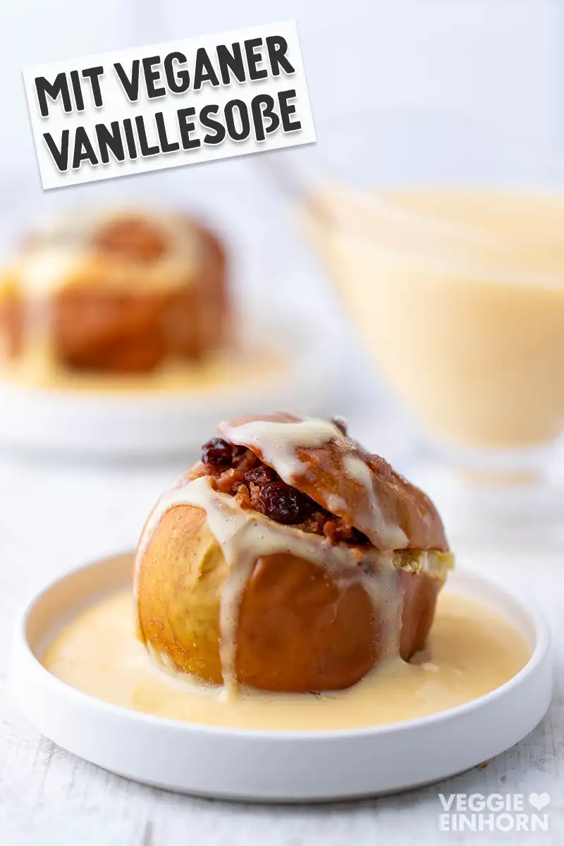 Ein veganer Bratapfel mit Vanillesoße auf einem weißen Teller, darüber der Text - Mit veganer Vanillesoße.