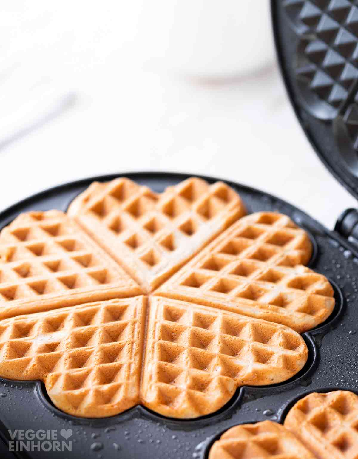 Frisch gebackene vegane Dinkelwaffel im Waffeleisen.
