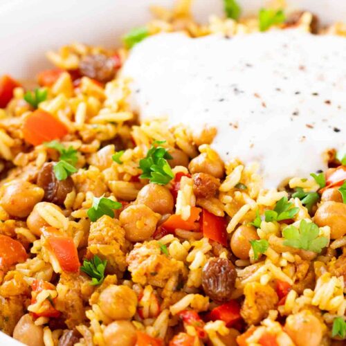 Nahaufnahme von veganer Hackfleisch-Reis-Pfanne mit Kichererbsen und veganer Joghurtsoße.