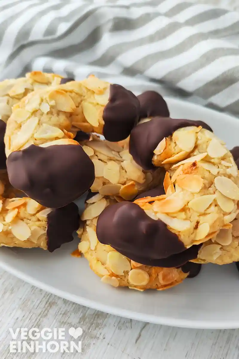 Nahaufnahme von veganen Mandelhörnchen mit vielen Mandelblättchen und dunkler Schokolade an den Enden.