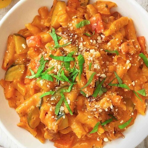 Teller mit veganer One Pot Pasta mit Paprika, Zucchini und getrockneten Tomaten