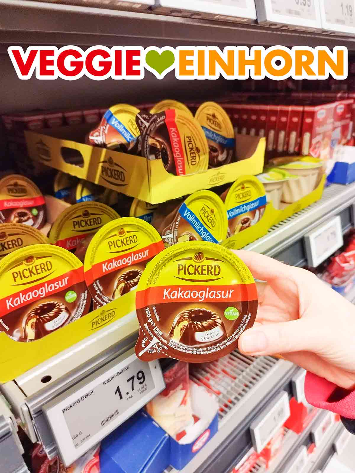 Eine Hand hält eine Packung vegane Pickerd Kakaoglasur im Supermarkt