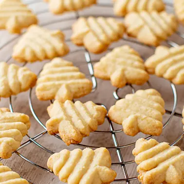 Vegane Butterplätzchen in Tannenbaumform auf einem Kuchengitter als Symbolbild für die Kategorie vegane Rezepte für Kekse und Plätzchen.