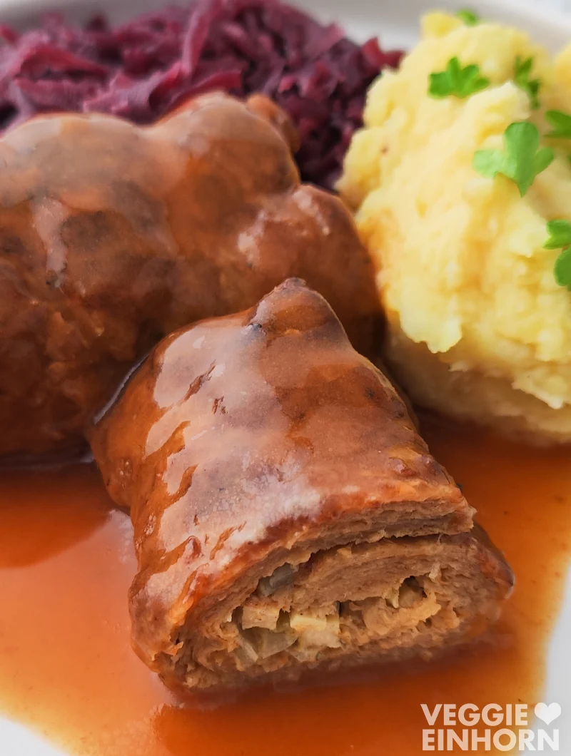 Nahaufnahme einer veganen Roulade aus Soja Big Steaks mit Bratensoße, Rotkohl und Kartoffelpüree.