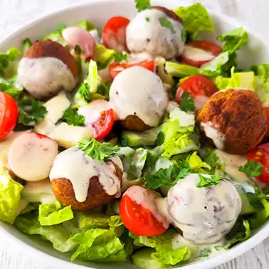 Bunter veganer Salat mit Falafelbällchen in einer weißen Schale als Symbolbild für die Kategorie Rezepte für vegane Salate.