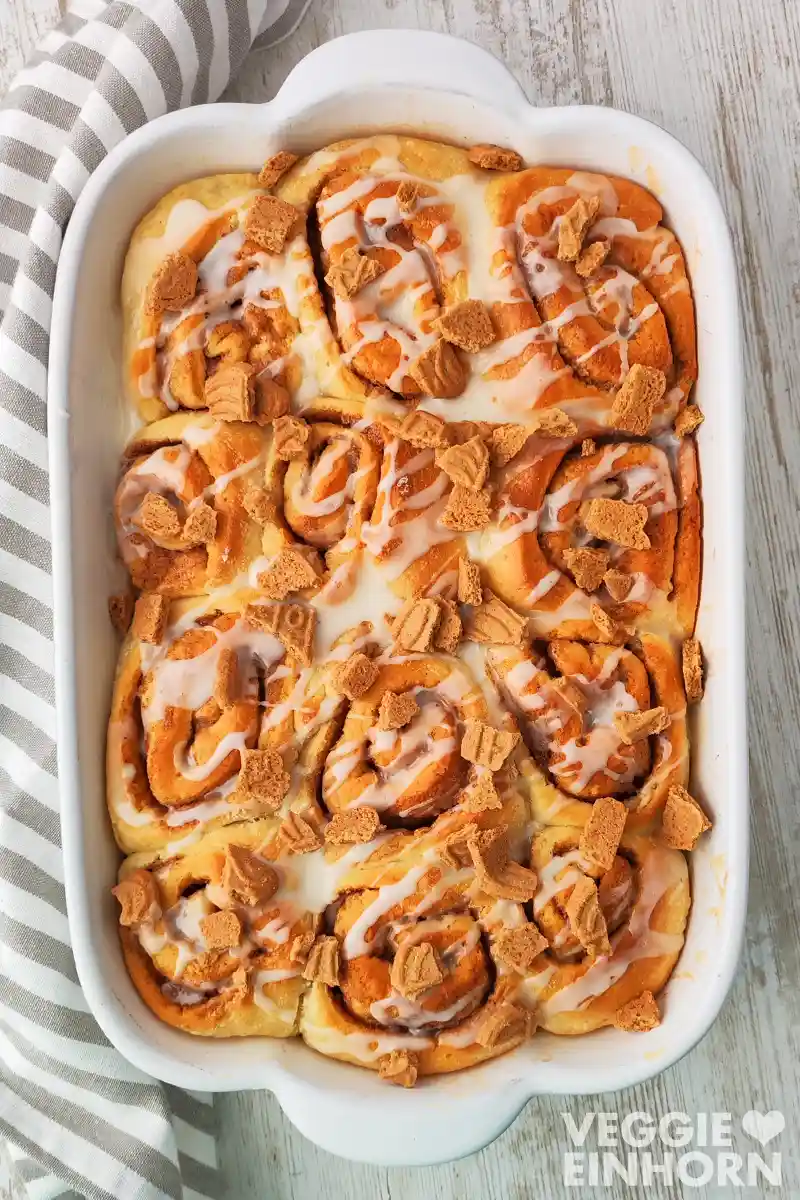 Auflaufform mit veganen Spekulatius-Zimtschnecken mit Zuckerglasur und Spekulatiusstückchen.