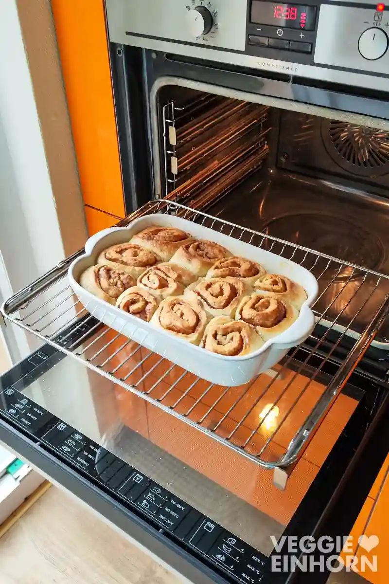 Vegane Spekulatius Zimtschnecken in einer weißen Auflaufform frisch aus dem Ofen auf dem Ofenrost. 