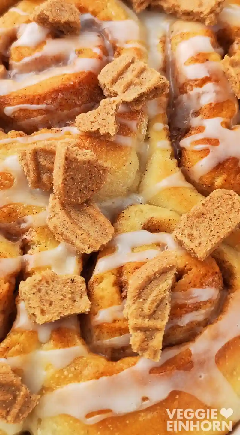 Nahaufnahme von veganen Spekulatius Zimtschnecken mit Zuckerguss und Spekulatius Stückchen.
