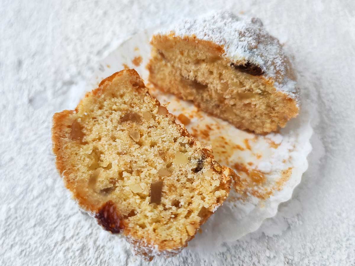 Zwei Hälften eines veganen Stollen Muffins auf heller Unterlage.