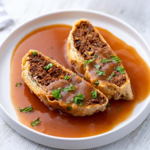 Veganer Beef Wellington Braten mit veganer Bratensoße auf einem Teller.